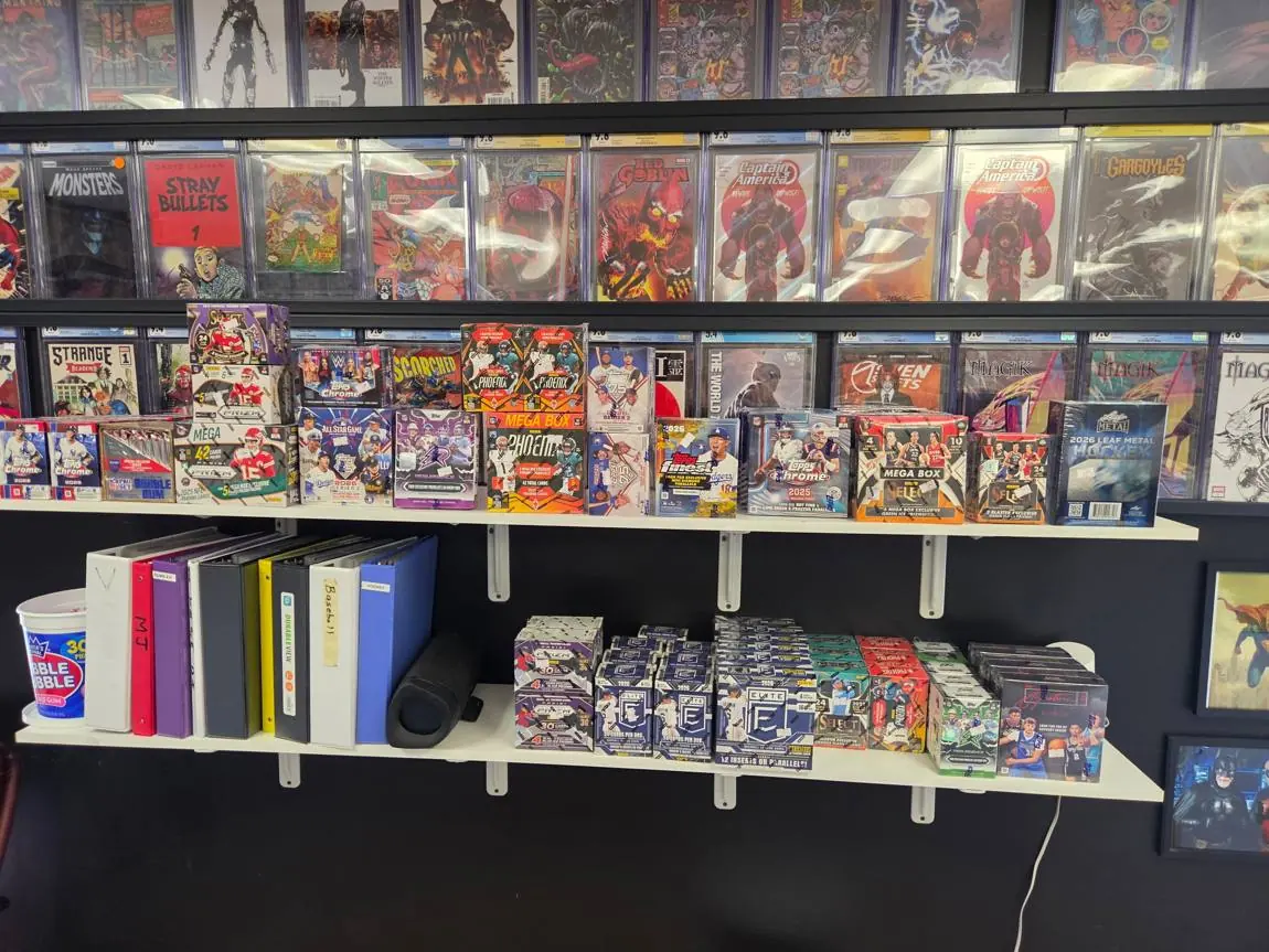 Shelves of sealed Prizm, Phoenix, Topps Chrome, Select and Elite boxes below a wall of graded comics